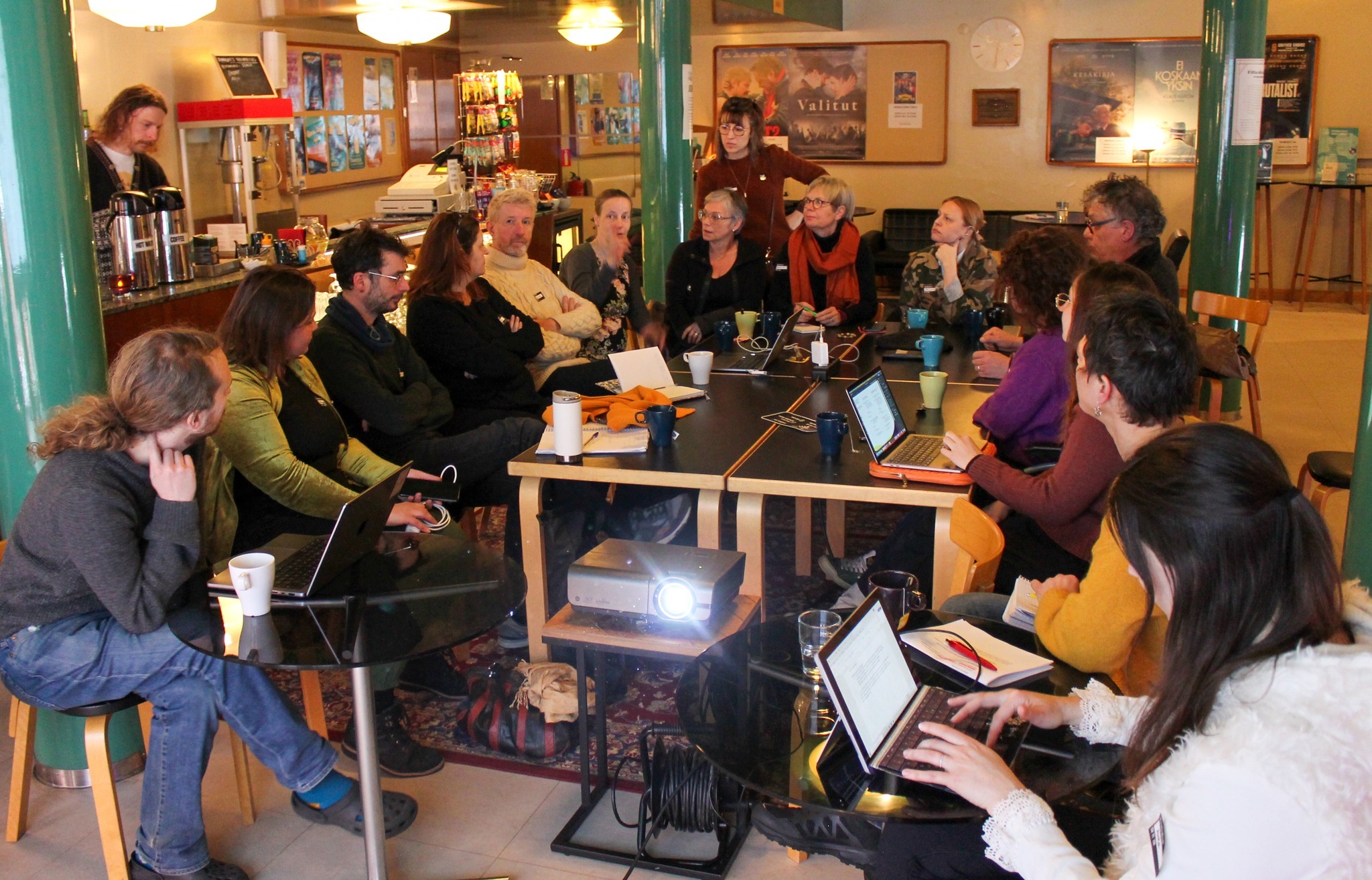 groupe de personnes autour d'une table, ils regardent un projecteur